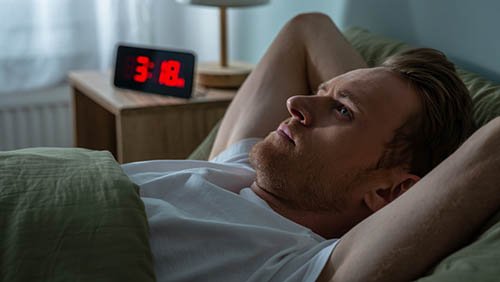 Мужчина лежит в кровати и не может уснуть